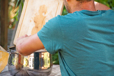 Rear view of man standing holding cutting board