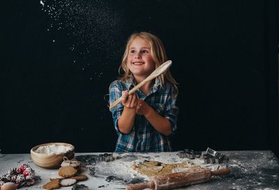 Portrait of girl holding wooden spoon baking christmas cookies