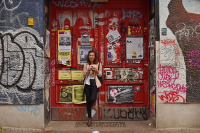 Portrait of smiling woman standing against wall