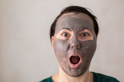 Portrait of shocked woman wearing facial mask against wall