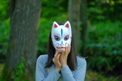 Portrait of woman wearing mask against tree