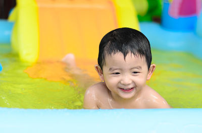 Smiling shirtless baby boy in wading pool