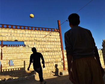 Rear view of man standing against blue sky