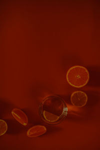 Photo of a glass with oranges half oranges and limes red background mood lifestyle still life photo