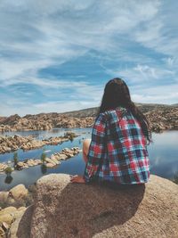 Rear view of woman sitting on a rock