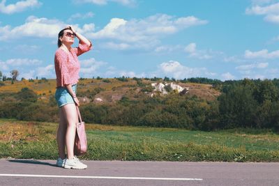 Side view of woman standing on road against sky