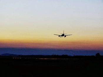 Airplane flying in sky at sunset