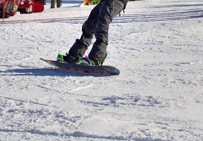 Low section of man skiing on snow covered landscape during winter