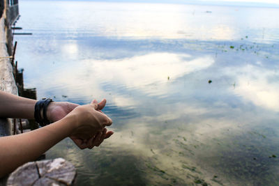 Cropped image of woman leaning on railing over lake