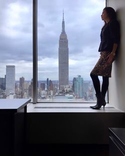 Woman standing on city against cloudy sky