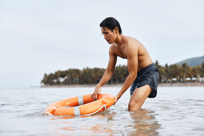 Shirtless man swimming in sea