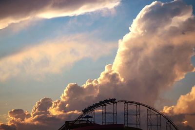 Low angle view of rollercoaster against sky at sunset