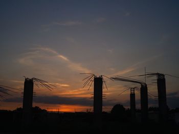 Silhouette cranes against sky during sunset