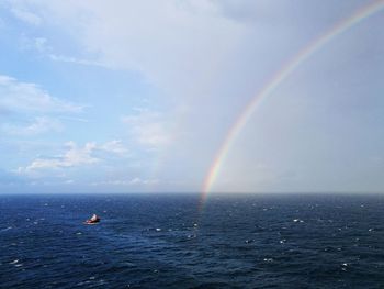 Scenic view of rainbow over sea against sky