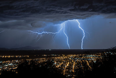 Lightning over cityscape against sky at night