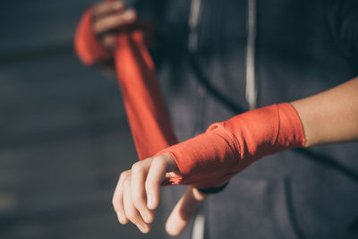 Midsection of athlete wrapping bandage on hand
