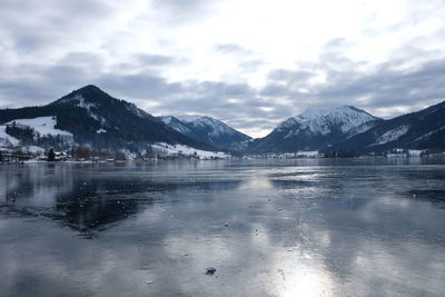 Scenic view of frozen lake by snowcapped mountains against sky