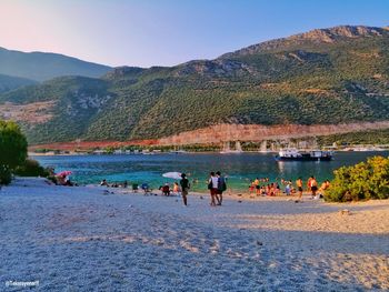 People on shore against sky