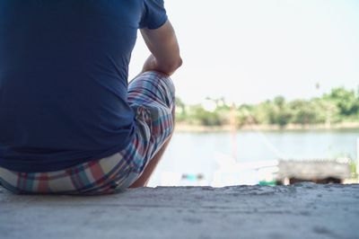 Low section of woman sitting against clear sky