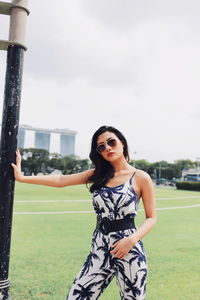 Portrait of smiling young woman standing against sky