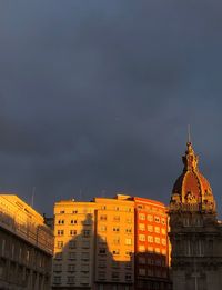 Buildings in city against cloudy sky