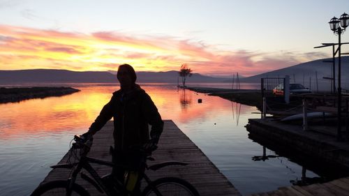 Silhouette man on sea against sky during sunset