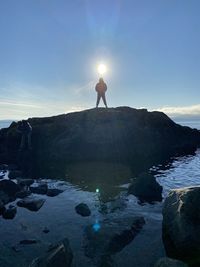 Man standing on rock against sky