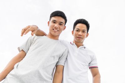 Portrait of happy friends standing against sky