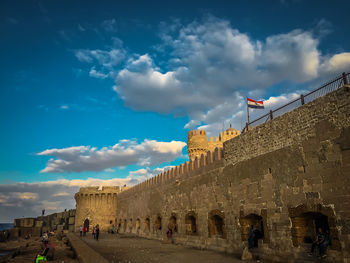 View of flags in city against cloudy sky