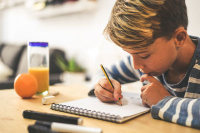 Boy making sketch on note pad at table