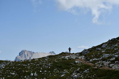 Man standing on rock by land against sky