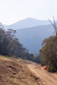 Dirt road by mountains against sky