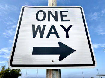 Low angle view of road sign against blue sky