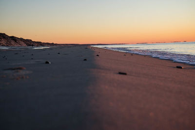 Scenic view of beach against clear sky during sunset