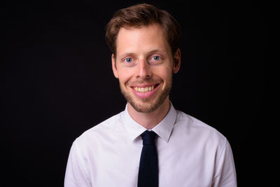 Portrait of young man against black background