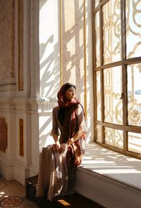 Young woman sitting on window