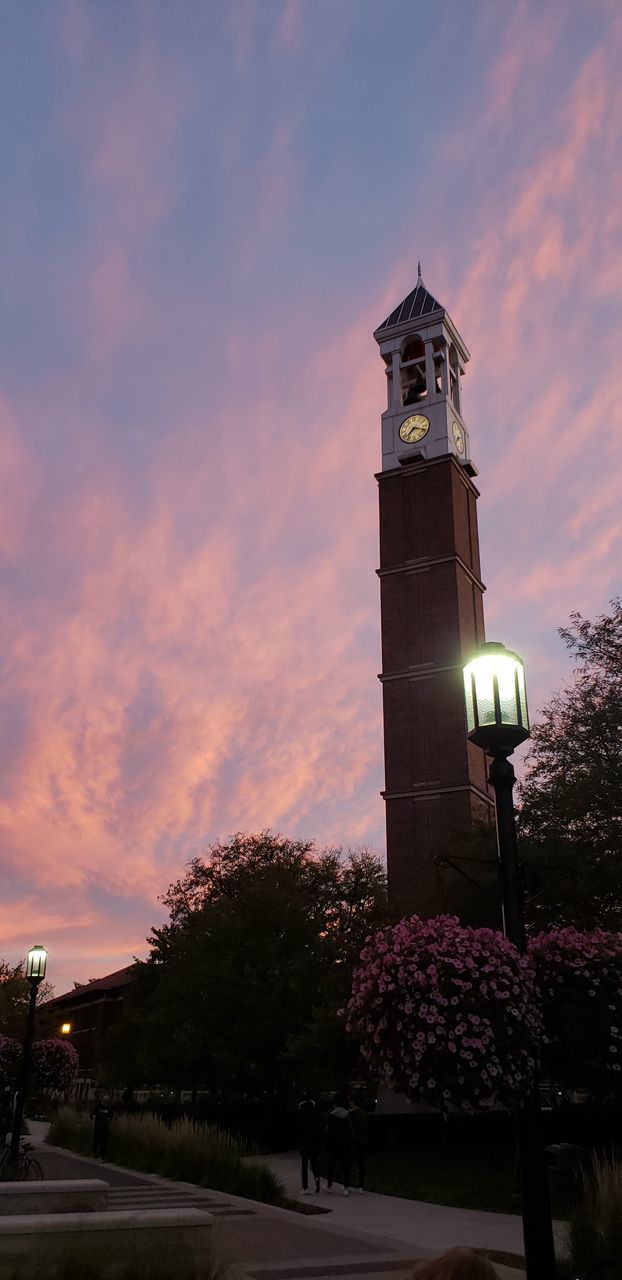 LOW ANGLE VIEW OF ILLUMINATED BUILDING BY STREET AGAINST SKY AT SUNSET