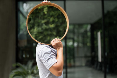 Midsection of man holding mirror