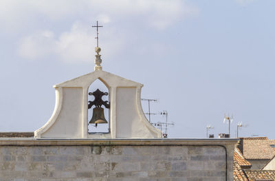 Low angle view of cross on building against sky