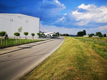 Empty road amidst field against sky