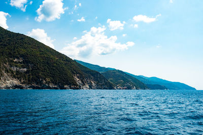 Scenic view of sea and mountains against blue sky