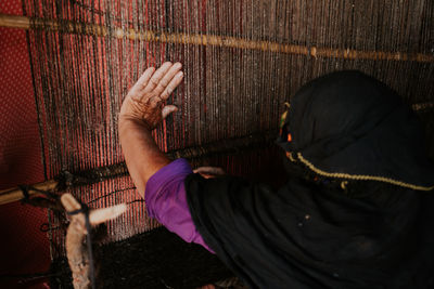 Rear view of woman working at loom