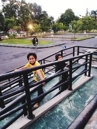 Portrait of boy standing on railing against trees