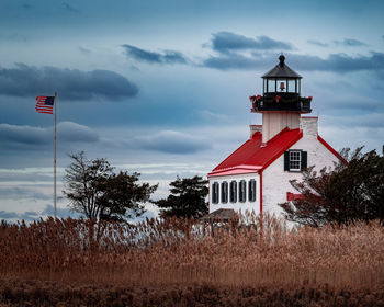 East point lighthouse with the american flag waving to the side.