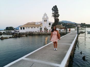 Woman standing on pier in sea against clear sky