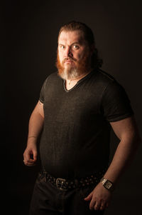 Portrait of man standing against black background