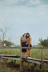 Woman sitting on tree against sky