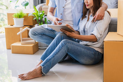 Midsection of woman using mobile phone while sitting on sofa