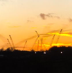 Silhouette electricity pylons against sky during sunset