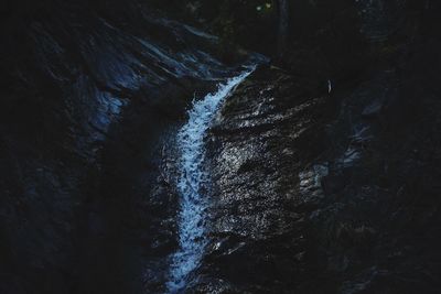 High angle view of stream flowing amidst rocks at night